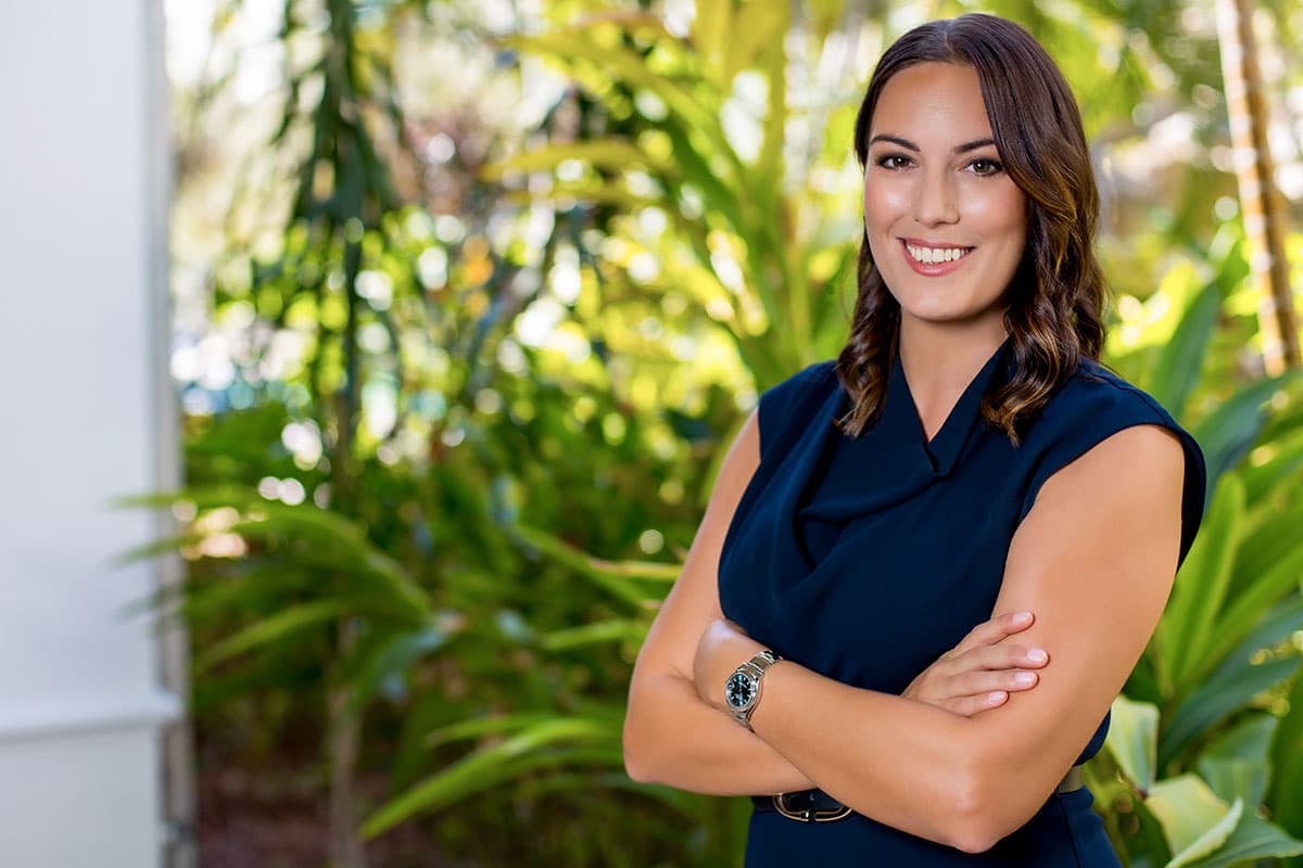 a lawyer who handles family law in the Cayman Islands stands outside with her arms crossed while smiling
