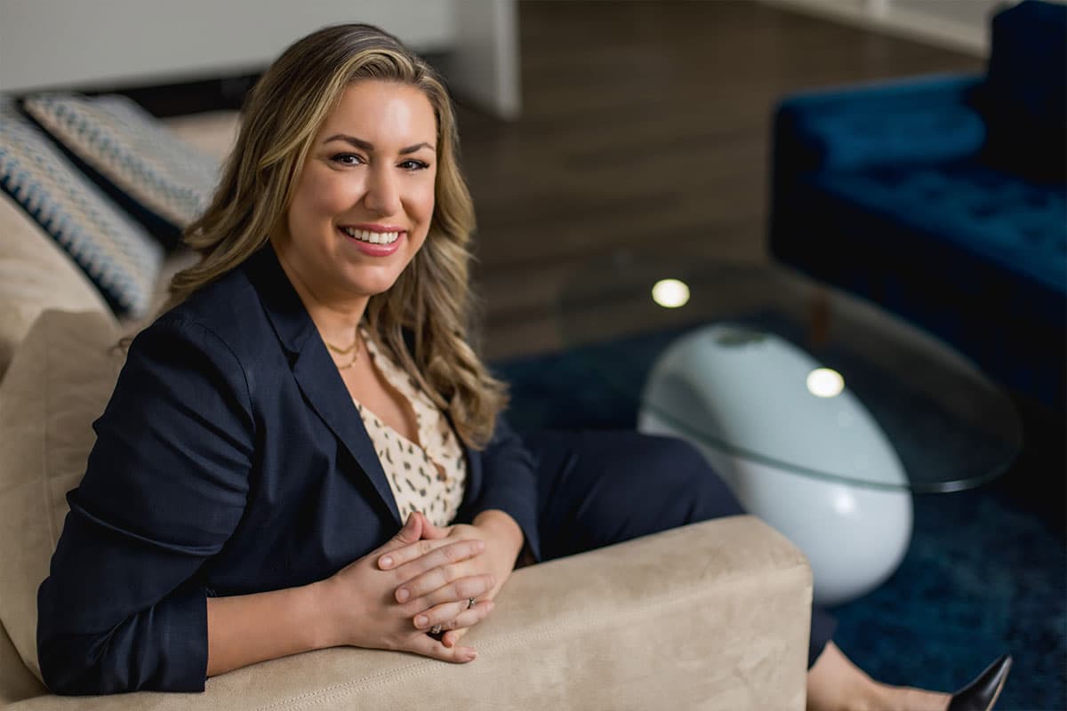 a property lawyer in the Cayman Islands sits on a couch and smiles